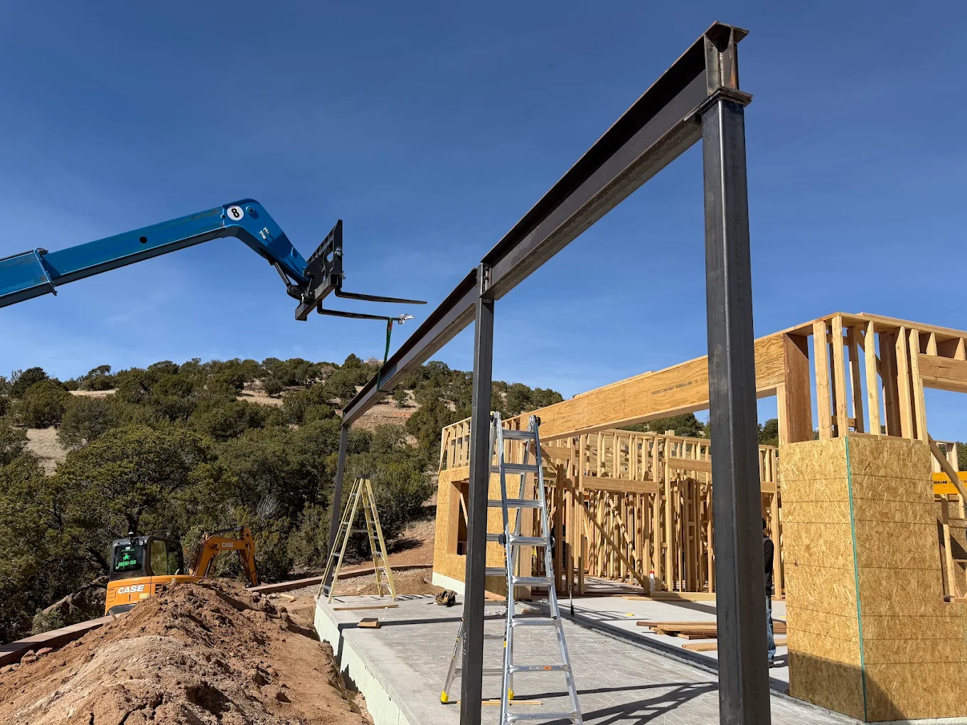 Steel beam set on a building frame with an excavator nearby